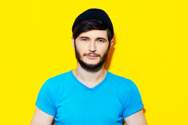 Retrato de estudio de chico joven con camisa azul sobre fondo de color amarillo.