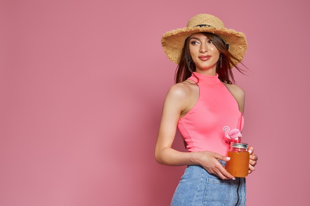 Retrato de estudio de dama hermosa adorable bastante linda sosteniendo un vaso de jugo en la mano con sombrero de paja ...