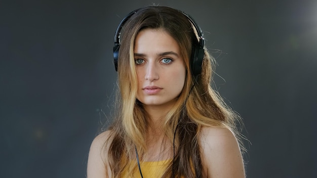 Retrato de estudio fondo gris joven hermosa estudiante chica seria lleva auriculares en la cabeza