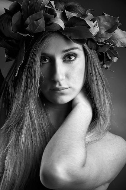 Retrato de estudio de una hermosa chica con una corona de hojas de roble laurel