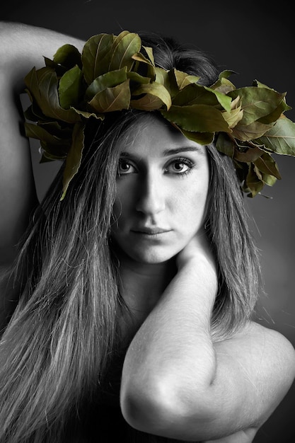Retrato de estudio de una hermosa chica con una corona de hojas de roble laurel
