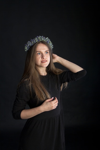 Retrato de estudio de hermosa chica morena en corona de flores secas en negro