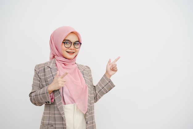 Retrato de estudio de una hermosa joven mujer de negocios musulmana con hijab rosa con gafas posando y mirando a la cámara sobre un fondo blanco
