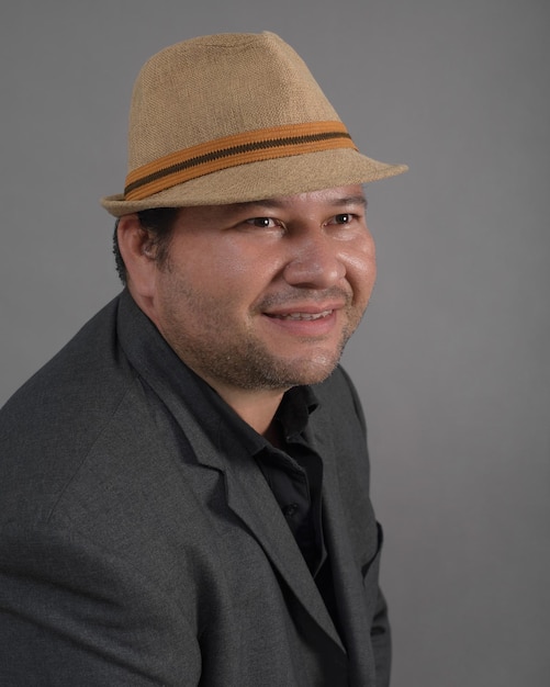 Retrato de estudio de hombre con actitud positiva con sombrero Fondo gris