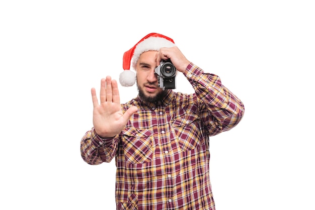 Foto retrato de estudio de hombre barbudo con sombrero de santa sosteniendo una cámara retro, haciendo una foto. fondo blanco aislado