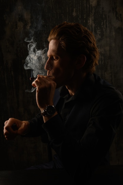 Foto retrato de estudio de hombre y cigarrillo de fumar sobre fondo oscuro