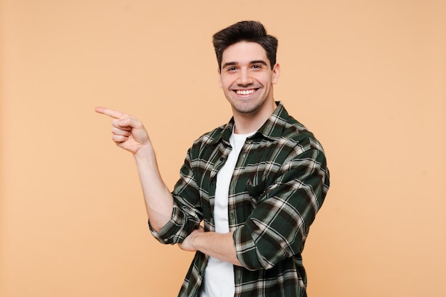 Retrato de estudio de un hombre guapo sonriente con una camisa a cuadros apuntando a un lado