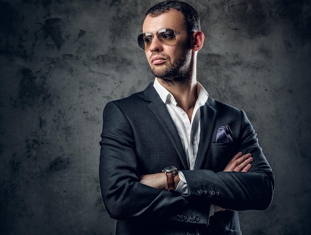 Retrato de estudio de un hombre serio y moderno con camisa blanca y chaqueta de negocios con fondo gris.