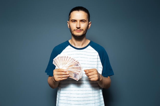 Retrato de estudio de un hombre serio que sostiene un montón de billetes de leu moldavo