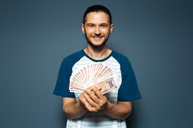 Retrato de estudio de un hombre sonriente sosteniendo un montón de billetes de leu moldavo