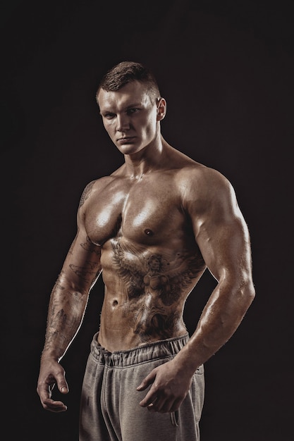 Retrato de estudio de un hombre tatuado atlético sin camisa