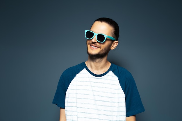 Retrato de estudio de joven apuesto hombre sonriente con gafas de sol