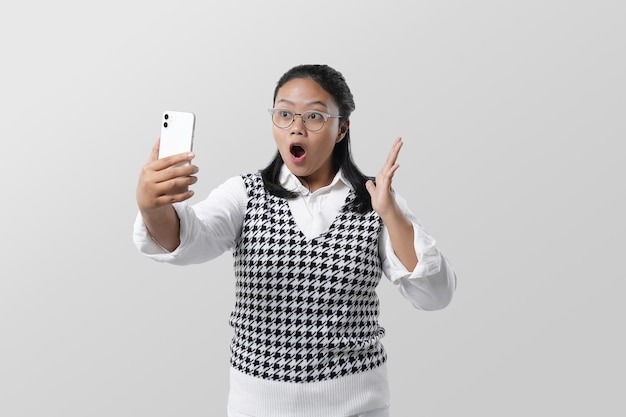 Retrato de estudio de una joven asiática haciendo selfie y videollamadas con expresión facial impactante