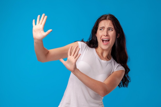 Retrato de estudio de una joven y bella mujer con una camiseta blanca sobre un fondo de pared azul. Personas sinceras emociones.