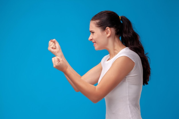 Retrato de estudio de una joven y bella mujer con una camiseta blanca sobre un fondo de pared azul. Personas sinceras emociones.