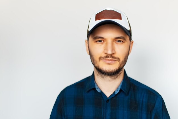 Foto retrato de estudio de un joven con camisa azul y gorra sobre fondo blanco