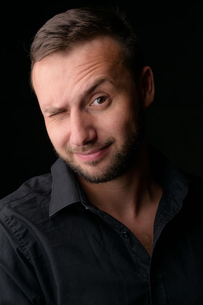 Retrato de estudio de un joven caucásico con un blazer negro mirando a la cámara de pie contra el fondo del estudio