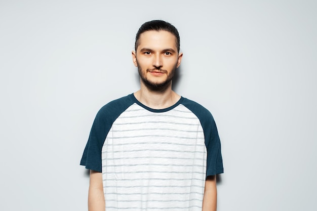 Retrato de estudio de un joven confiado en camisa de fondo blanco