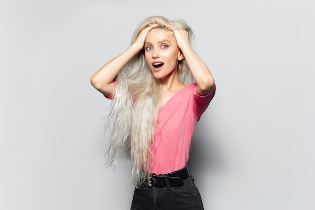 Retrato de estudio de la joven felicidad niña sorprendida con las manos en la cabeza aislado sobre fondo blanco.