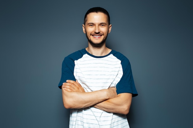 Retrato de estudio de joven feliz con los brazos cruzados sobre fondo azul.