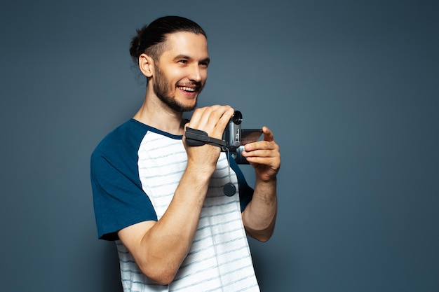 Retrato de estudio de un joven feliz con una cámara de video digital en las manos