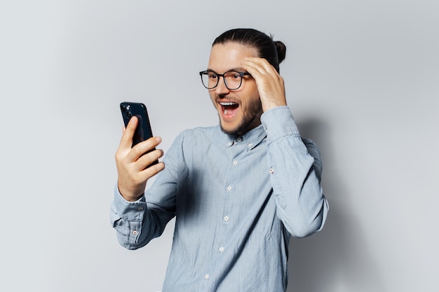 Retrato de estudio de un joven hombre feliz usando un teléfono inteligente con fondo blanco