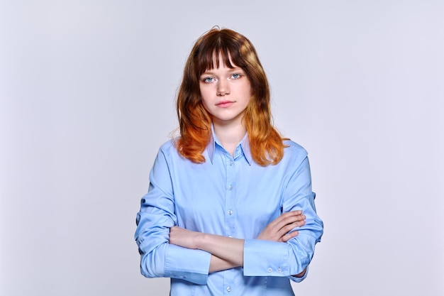 Retrato de estudio de una joven mujer seria y triste mirando a la cámara con un fondo claro