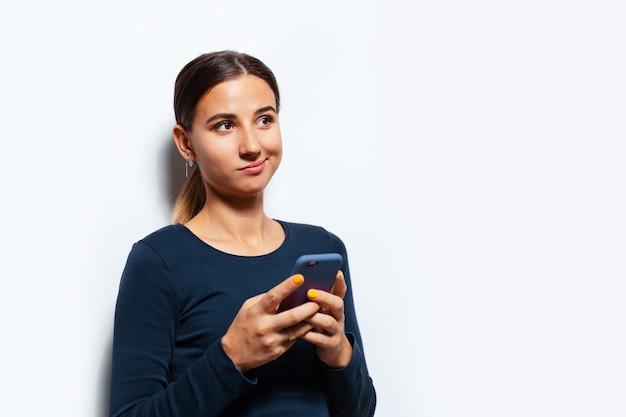 Retrato de estudio de joven pensativa con smartphone