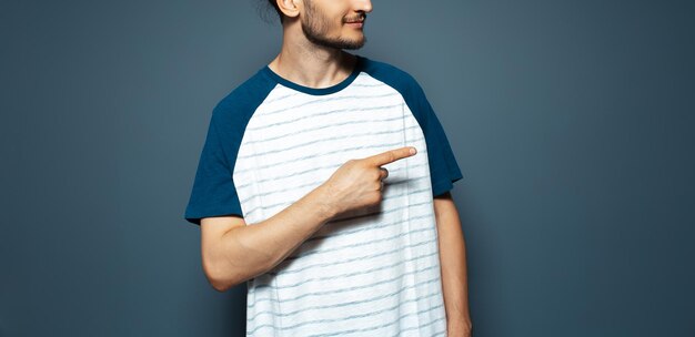 Retrato de estudio de un joven que señala con el dedo lejos Pancarta panorámica Fondo azul