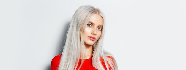 Retrato de estudio de una joven rubia bonita con camisa roja en una vista panorámica de fondo blanco