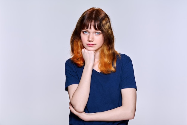 Retrato de estudio de una joven seria mirando a la cámara sobre un fondo claro