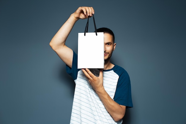 Retrato de estudio de un joven sosteniendo una bolsa blanca reutilizable cerca de sus ojos