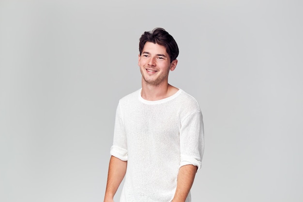 Retrato de estudio de joven vistiendo camiseta blanca sonriendo fuera de cámara