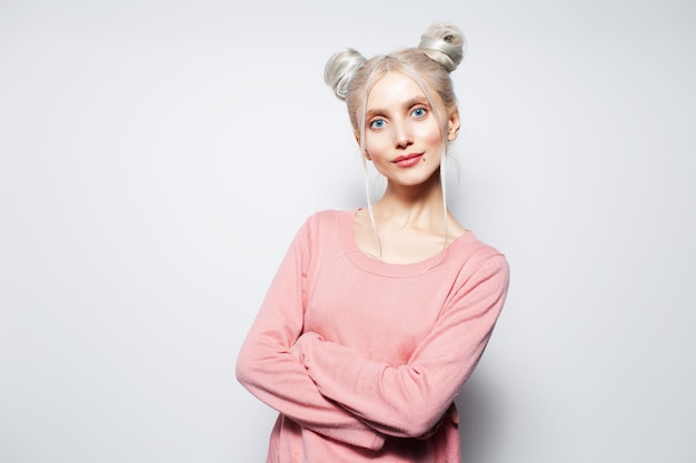 Retrato de estudio de linda chica rubia con los brazos cruzados sobre fondo blanco.