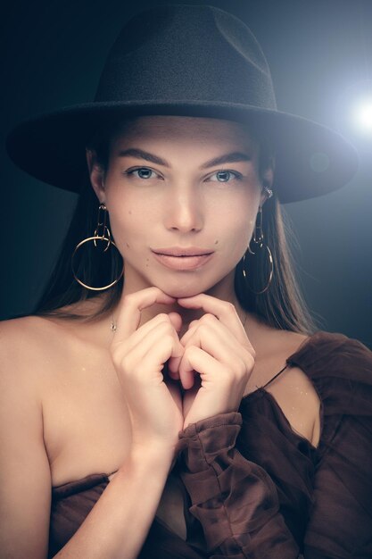 Retrato de estudio de moda de una hermosa joven con sombrero negro sobre un fondo gris