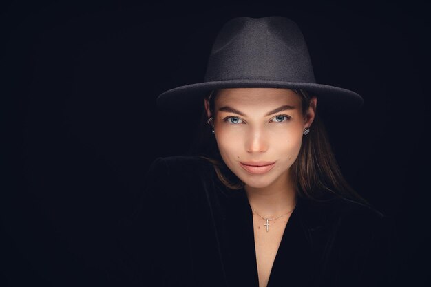 Retrato de estudio de moda de una hermosa joven con sombrero negro sobre un fondo negro