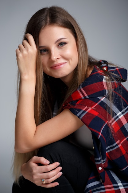 Retrato de estudio de moda de una hermosa niña en una camisa a cuadros en una pared gris