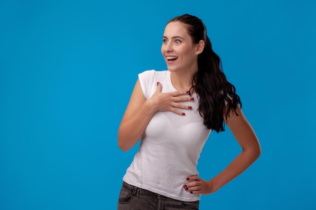 Retrato de estudio de una mujer hermosa joven en una camiseta blanca contra un fondo de pared azul personas s ...