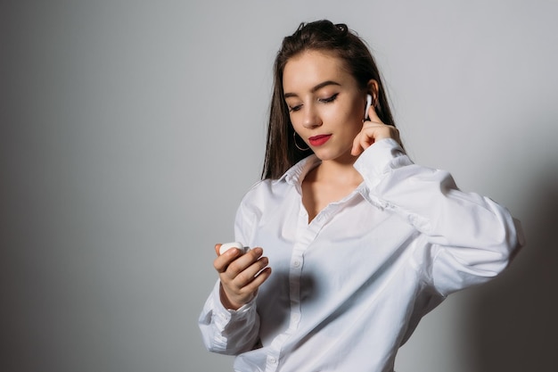 Retrato de estudio de mujer joven escuchando música en auriculares inalámbricos mujer sonriente escuchando