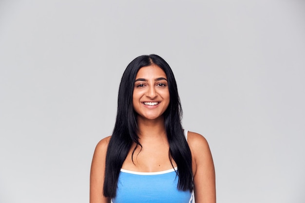 Retrato de estudio de mujer joven feliz positiva sonriendo a la cámara