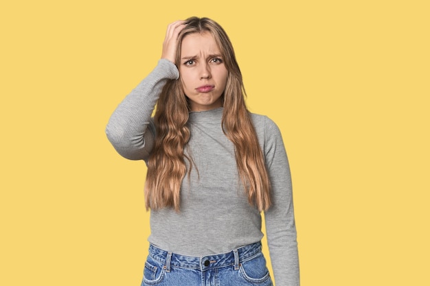 Retrato de estudio de una mujer rubia caucásica cansada y muy somnolienta manteniendo la mano en la cabeza