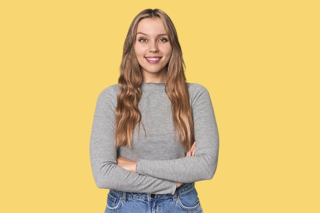 Retrato de estudio de una mujer rubia caucásica que se siente segura cruzando los brazos con determinación