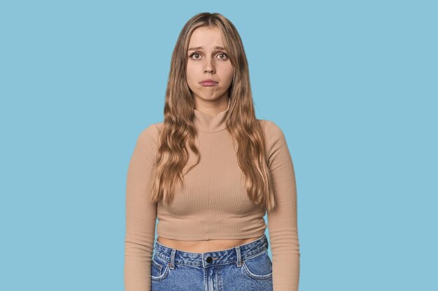 Foto retrato de estudio de una mujer rubia caucásica con rostro triste y serio, sintiéndose miserable y disgustada.