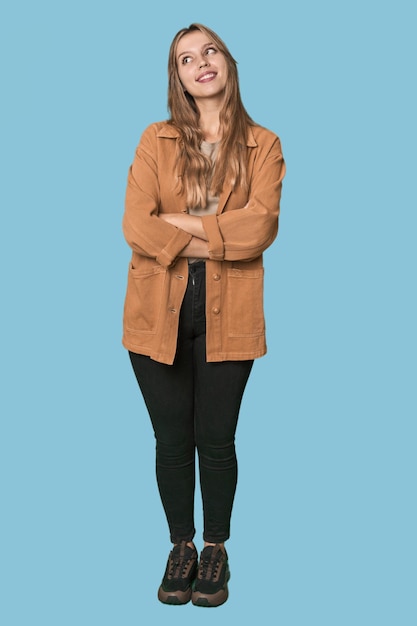 Foto retrato de estudio de una mujer rubia caucásica sonriendo con confianza con los brazos cruzados