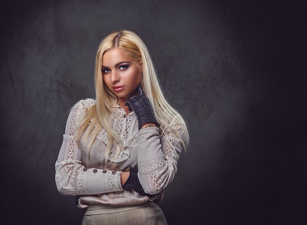 Retrato de estudio de mujer rubia pasada de moda sobre fondo gris.