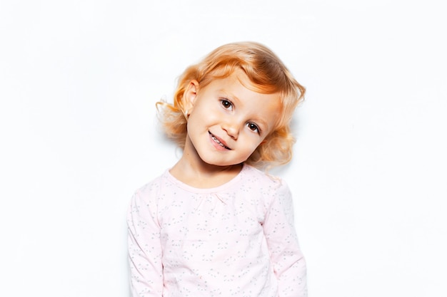 Retrato de estudio de niña sonriente con cabello rubio rizado