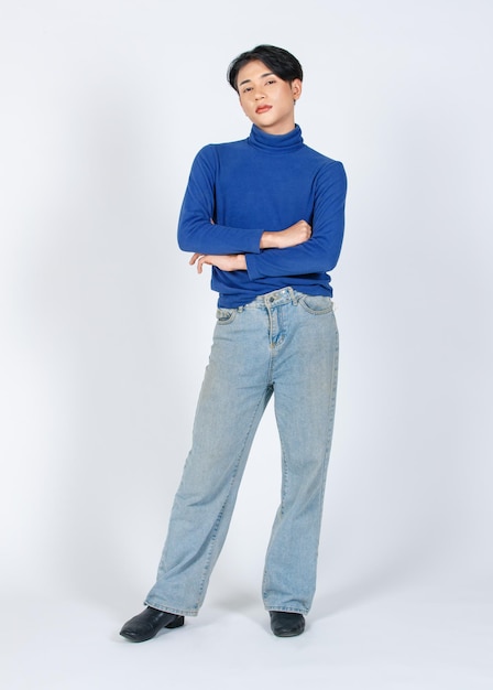 Retrato de estudio de recorte aislado foto de cuerpo completo de modelo masculino gay joven asiático en jeans de mezclilla de camisa de manga larga de cuello alto con zapatos de cuero de tacón alto de pie posando mirando a la cámara sobre fondo blanco