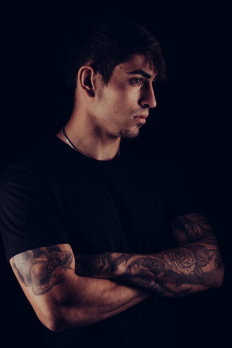Retrato de estudio vertical con luces de colores de un joven con los brazos cruzados.