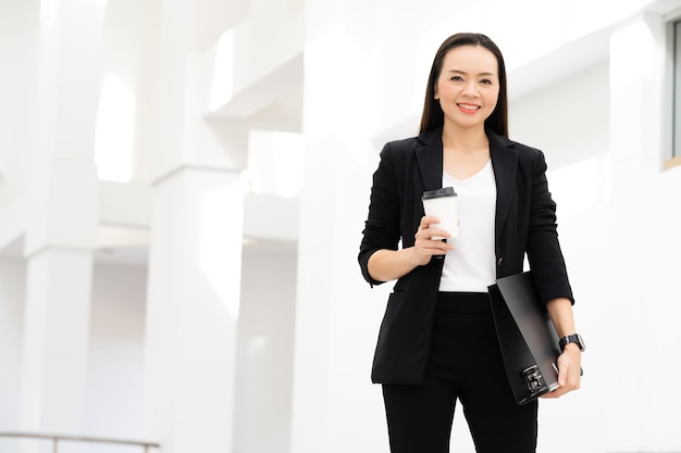 Retrato de una exitosa empresaria asiática de mediana edad sosteniendo café sonriendo a la cámara