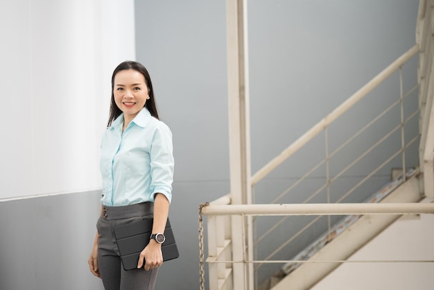 Retrato de una exitosa empresaria asiática de mediana edad sosteniendo tablet sonriendo a la cámara